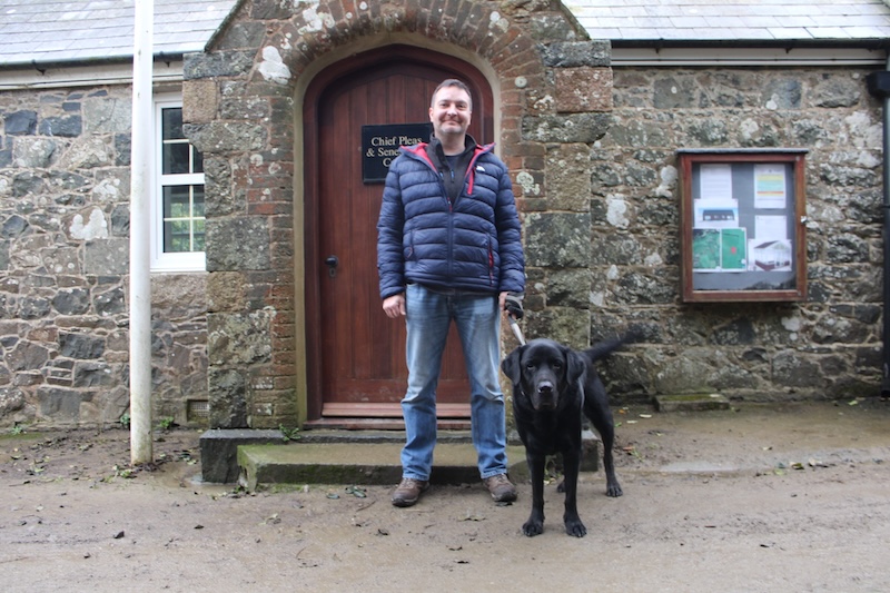 Pictured: Conseiller John Guile stands with his black Labrador Freddy, outside of Sark's Chief Pleas.
