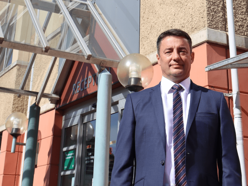 A man ina shit stands in front of a government building.