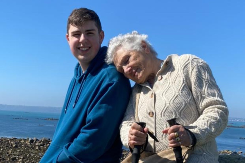 A young man and an old lady in front of the sea.