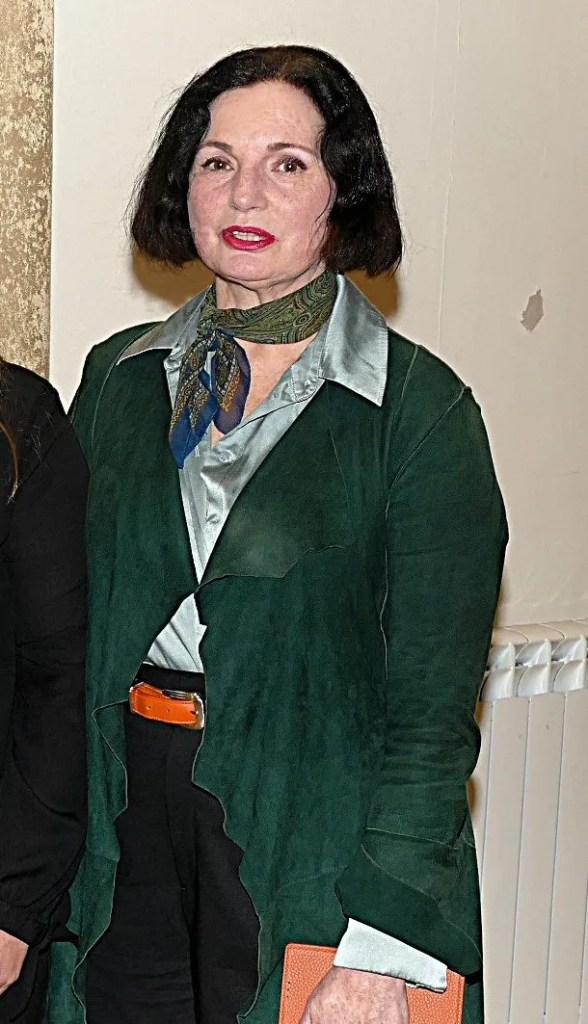 A woman with dark har in a green jacket.