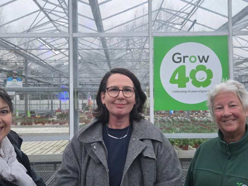 Three women in front of a Greenhouse. A sign reads Grow 40.