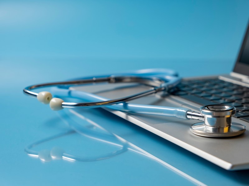 A laptop with a doctor's stethoscope on the keyboard.