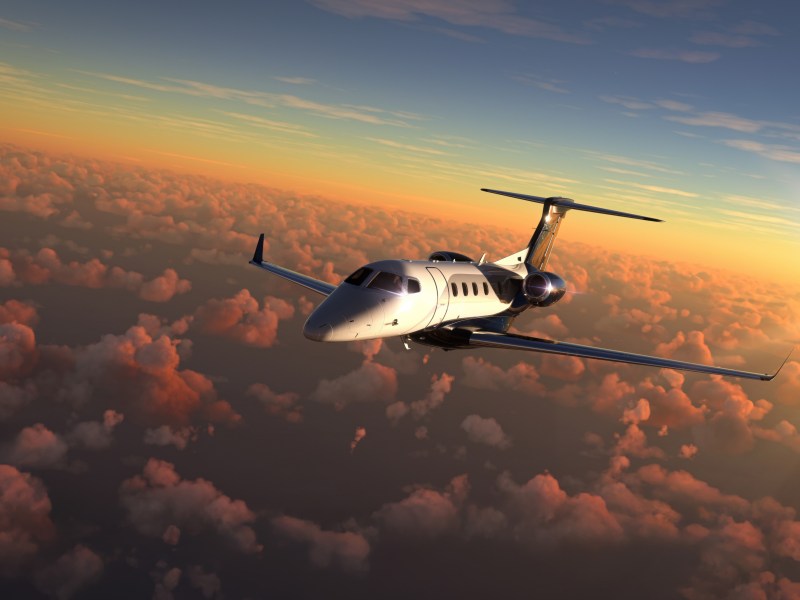 A private jet flies above the clouds close to sunset.