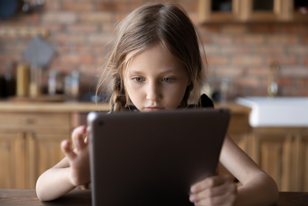 A young girl looks intrigued as she uses an iPad.