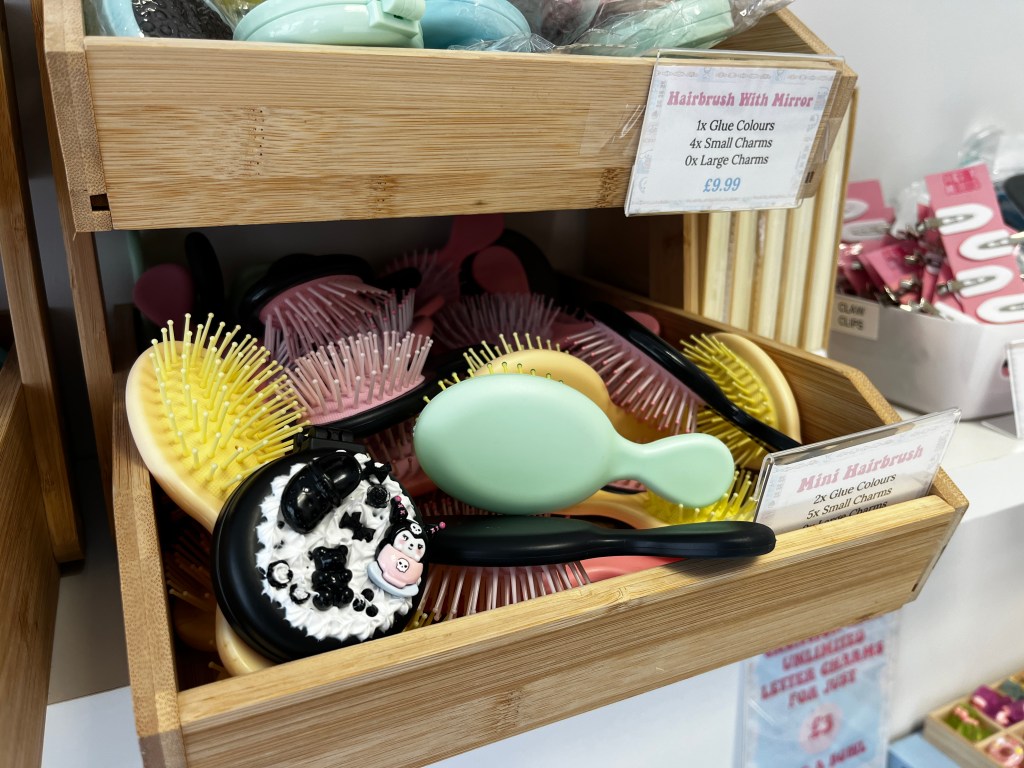 Wooden display shelves filled with pastel hairbrushes and hand mirrors inside a gift shop.