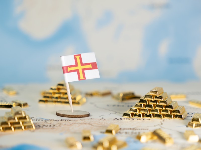 A model of piles of small gold bars, with a world map in the background a small Guernsey flag planted.