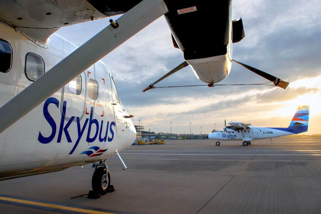 Two Twin Otter planes on a runway. They're small planes with propellors.