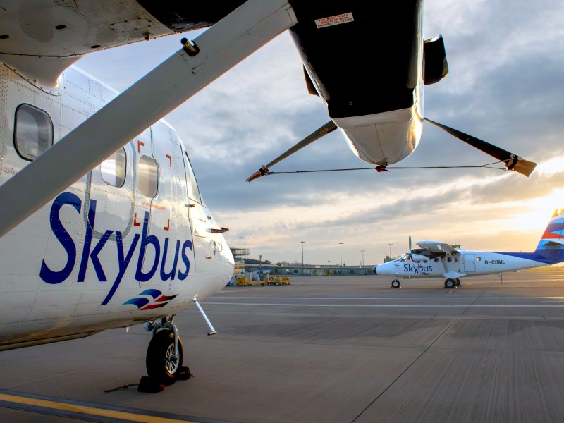 Two Twin Otter planes on a runway. They're small planes with propellors.