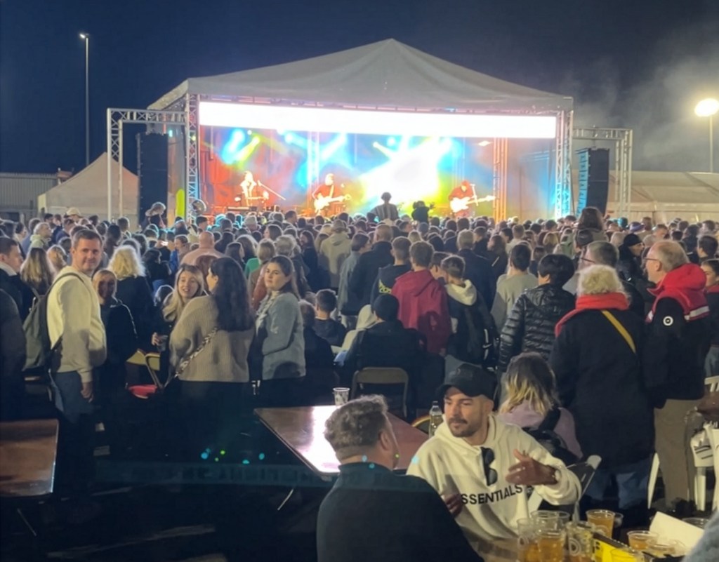 Revellers partying in front of a tent, with a band playing.