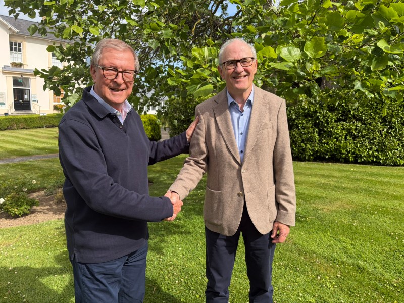 Two men in a garden shaking hands.