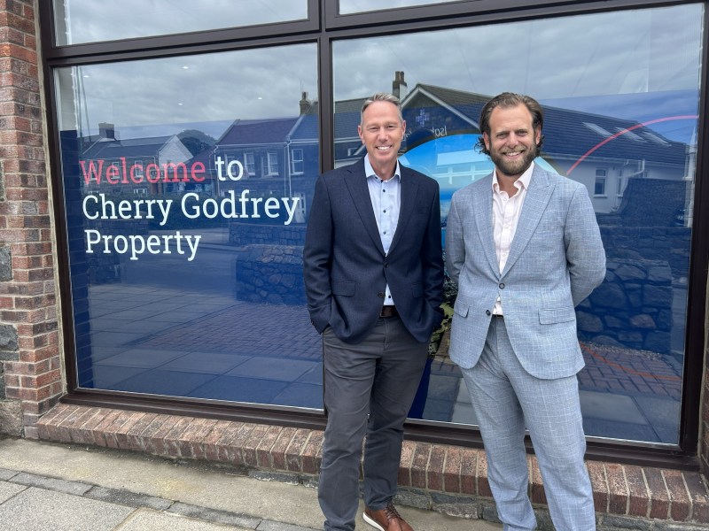 Two businessmen in suits standing in front of Cherry Godfrey's shop window.
