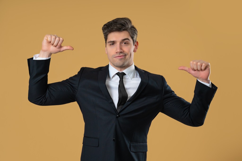 Male corporate figure gestures toward his chest with cocky smile, radiating self-importance and dominance. Great for business attitude themes, self-promotion, satire or branding
