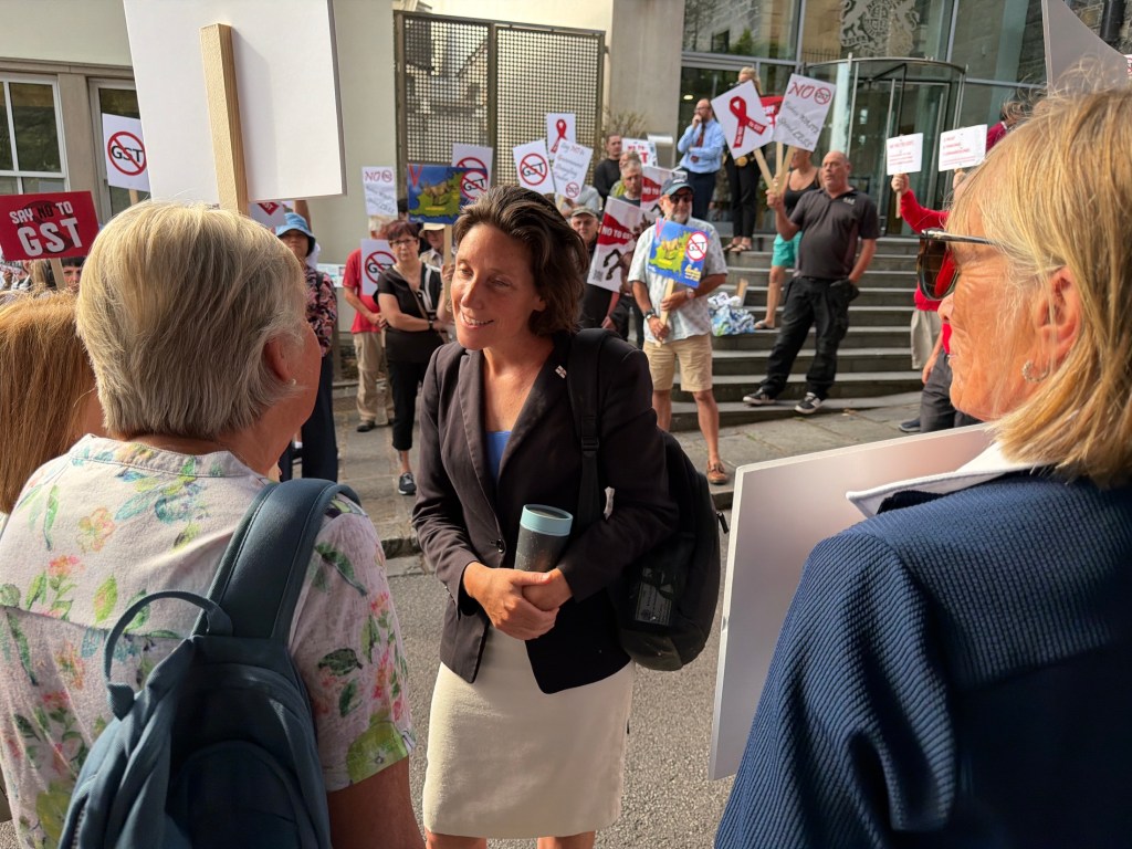Lindsay de Sausmarez speaks to a woman in a crowd at an anti-GST demo.