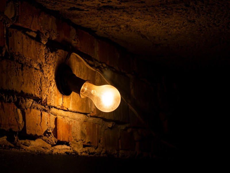 A fading lightbulb in a dark alley.