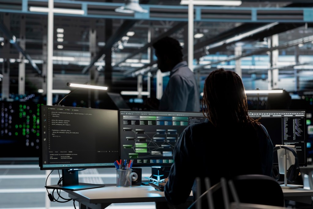 System administrator in data center uses AI technology for machine learning workloads. IT professional in server farm facility using artificial intelligence to perform demanding computing tasks.