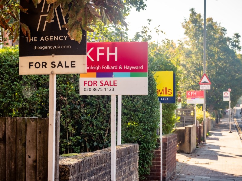 Estate agent signs advertising houses for sale on row of terraced houses.