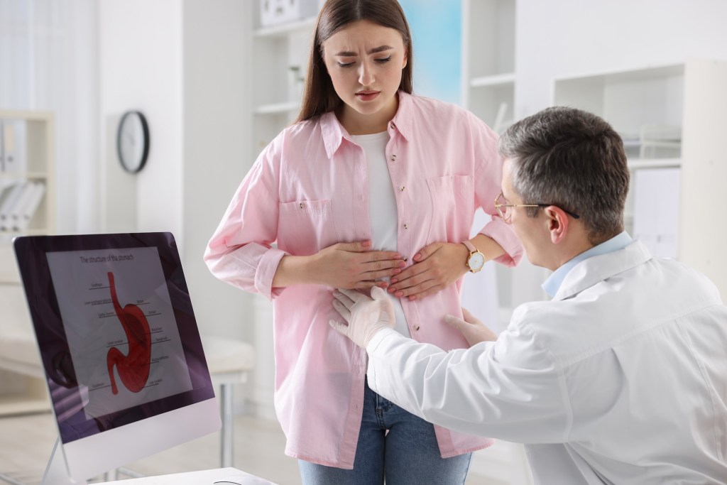 Gastroenterologist examining patient with stomach pain in clinic