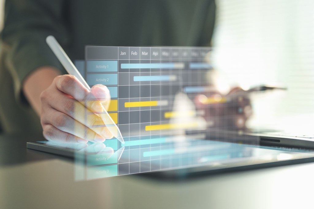project, gantt, timeline, schedule, tasks, planning, milestone, management, chart, deadline, gantt chart, A hand using a stylus to update a digital Gantt chart showing project tasks and timelines.