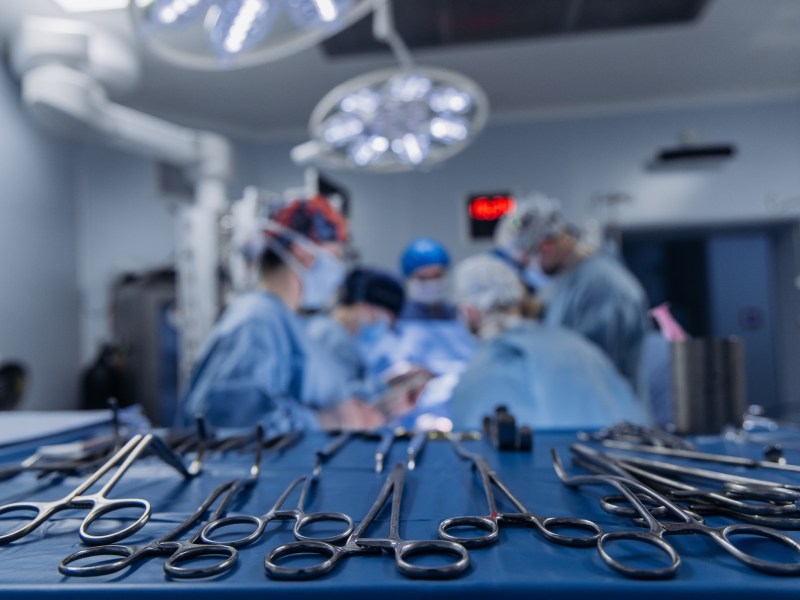Team of surgeons performing operation in modern operating room wearing sterile surgical attire. Surgery concept.