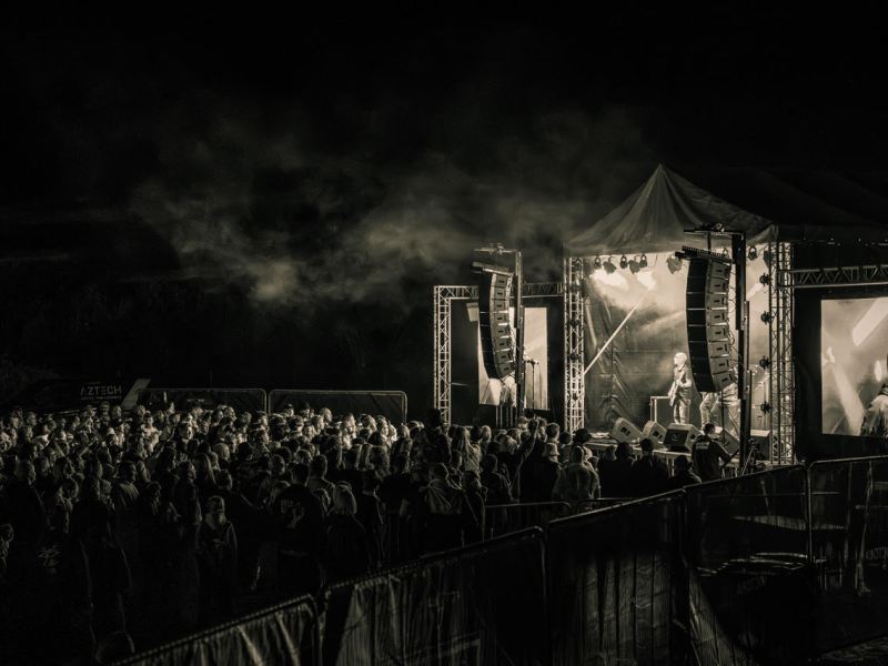 A back and white photo of a side on crowd watching people perform on stage