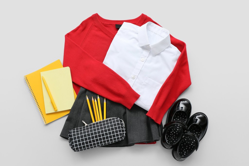 Stylish school uniform with different stationery on grey background