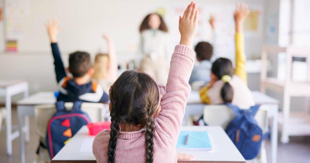 Learning, question and hands raised with girl in classroom for education, discussion and knowledge. Help, studying and teacher with children and woman at school for why, scholarship and answer