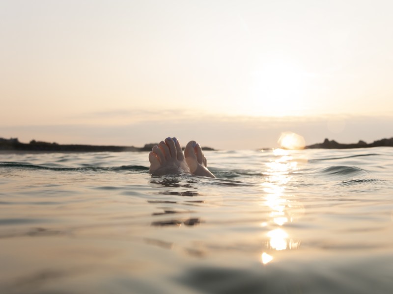 Feet bobbing on the water during sunset in the ocean. Sunset sea swim on the islands of Guernsey