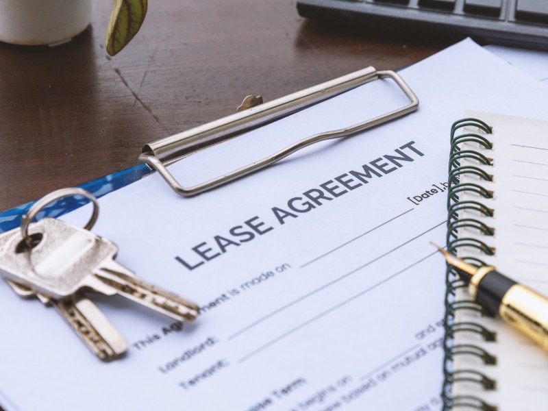Residential Lease Agreement Document with Property Keys and Clipboard on Office Desk